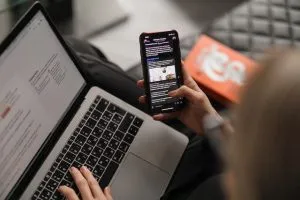 Person looking at a mobile phone and laptop
